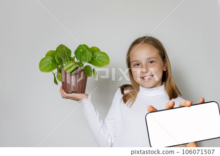 Happy smiling child holding green plant and showing smartphone  106071507