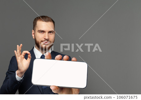 Handsome businessman with OK gesture and smartphone with blank empty white screen display  106071675
