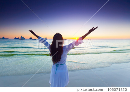 Woman raising arms to sunrise Woman raising arms to sunrise 106071850
