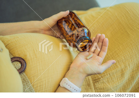 Prenatal Vitamins. Portrait Of Beautiful Smiling Pregnant Woman Holding Transparent Glass Jar With Pills, Taking Supplements For Healthy Pregnancy While Sitting On Couch At Home, Free Space Prenatal Vitamins. Portrait Of Beautiful Smiling Pregnant Woman Holding Transparent Glass Jar With Pills, Taking Supplements For Healthy Pregnancy While Sitting On Couch At Home, Free Space 106072091