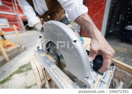 carpenter cutting wooden beam with electrical saw carpenter cutting wooden beam with electrical saw 106072301