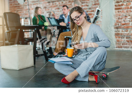 Woman in lofty office sitting on the floor 106072319