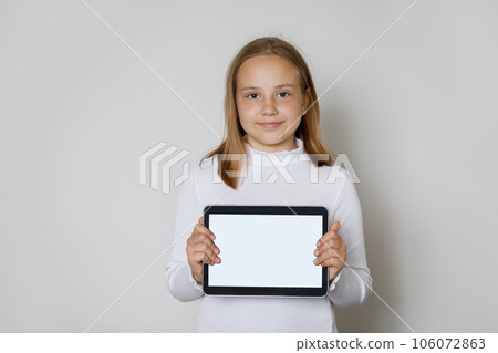 Smiling young child girl holding tablet gadget with empty white screen display for new application  106072863