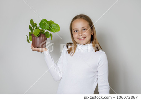 Young girl showing green plant in pot on white background. Hobby, leisure, gardering Young girl showing green plant in pot on white background. Hobby, leisure, gardering 106072867
