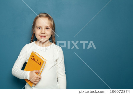 Child student girl with Deutsch language book on the background of blue chalkboard Child student girl with Deutsch language book on the background of blue chalkboard 106072874