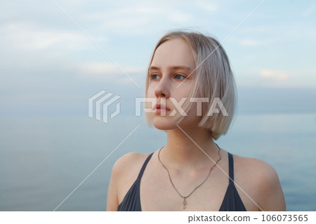 Portrait of blonde woman standing on the background of blue sea and cloudy sky 106073565
