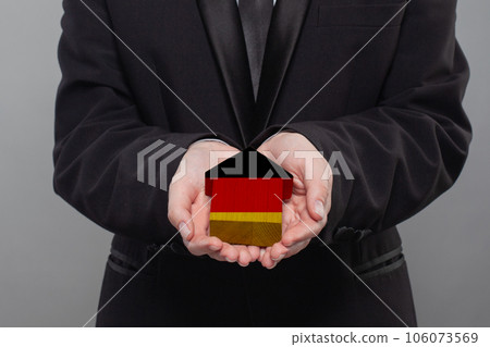 German person holding wooden house with flag of Germany Finance, investment, mortgage 106073569