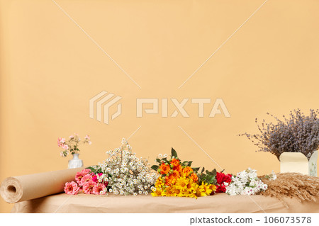 Empty florist workplace with many different flowers on table isolated over beige copy space background, advertisement area, mockup for promotion. 106073578
