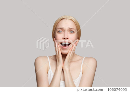 Portrait of happy surprised woman touching her face with hands isolated on grey background. Portrait of happy surprised woman touching her face with hands isolated on grey background. 106074093