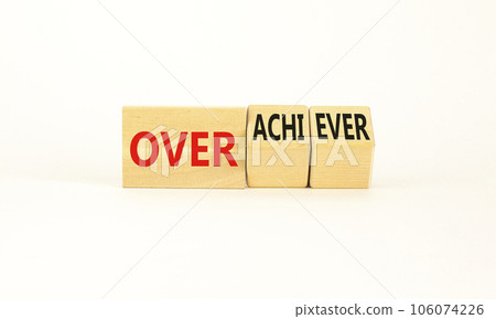 Achiever or overachiever symbol. Businessman turns wooden cubes and changes word Achiever to Overachiever. Beautiful white background. Business achiever or overachiever concept. Copy space. 106074226