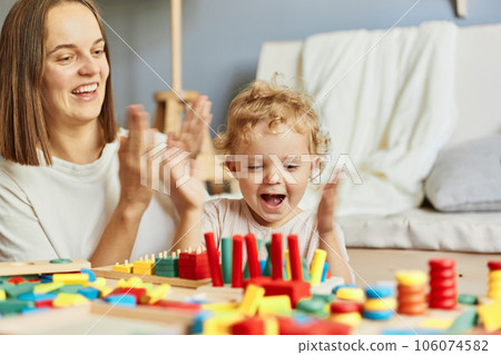 Cognitive puzzle challenges. Happy family gatherings. Parenting adventures together. Teacher or mother playing with baby with logical toys at home interior Cognitive puzzle challenges. Happy family gatherings. Parenting adventures together. Teacher or mother playing with baby with logical toys at home interior 106074582
