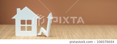 Rising property values. Increasing the cost of housing. Banner with white house model and graphic arrow pointing up close up on brown background. copy space. 106076684