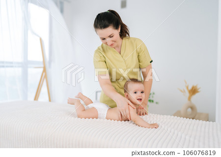 Side view of young loving mother giving back massage toddler son lying on bed, feeling love, express caress. Happy mom making gentle relaxing massage on cheerful baby. Concept of infant healthcare. 106076819