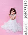 Beautiful little kid girl in white dress sitting on pink background. Happy birthday 106077139
