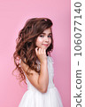 cute little girl in a beautiful dress with hairstyle and make-up on a pink background 106077140