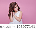 Close-up portrait of beautiful kid girl in dress looking away on pink background 106077141