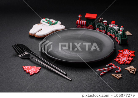 Empty dark ceramic plate with elements of Christmas decorations Empty dark ceramic plate with elements of Christmas decorations 106077279