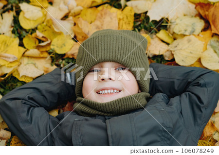 cute little boy laying on ground covered with yellow fallen leaves cute little boy laying on ground covered with yellow fallen leaves 106078249