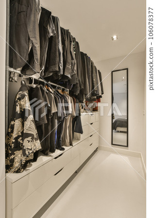 a closet with clothes hanging on the wall and an open door that leads to a walk - in dressing room 106078377