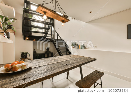 a dining table with fruit on it and an open staircase in the back wall to the room is bright white a dining table with fruit on it and an open staircase in the back wall to the room is bright white 106078384