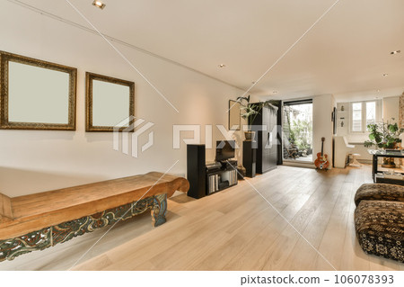 a living room with wood flooring and white walls in the center of the room is a large mirror on the wall a living room with wood flooring and white walls in the center of the room is a large mirror on the wall 106078393