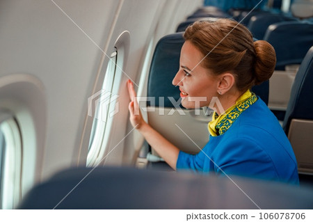 Joyful woman stewardess looking out the window in airplane 106078706