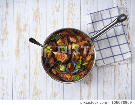 mussels cooked in a tomato sauce on a pan on a wooden table, top view. mussels cooked in a tomato sauce on a pan on a wooden table, top view. 106078969