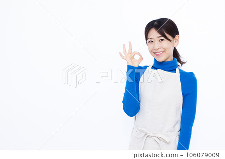 A housewife in her thirties doing an OK sign in front of a white background A housewife in her thirties doing an OK sign in front of a white background 106079009