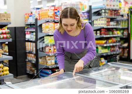 Positive woman chooses frozen convenience foods in supermarket 106080269