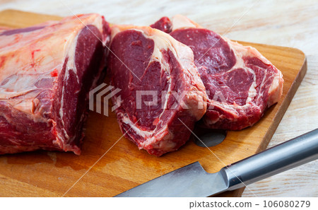 Sliced beef pieces on wooden board with knife 106080279