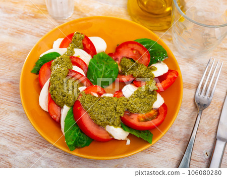 Caprese salad with tomatoes, mozzarella, basil, pesto 106080280