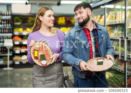 couple showing frozen pizzas bought in grocery store couple showing frozen pizzas bought in grocery store 106080325