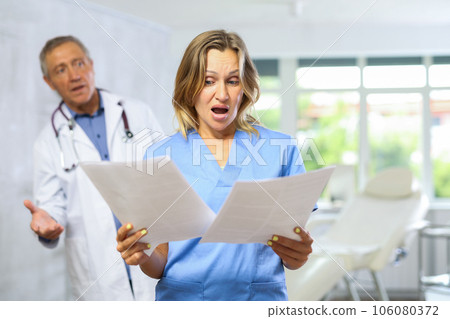 Elderly man doctor scolding adult female medic 106080372