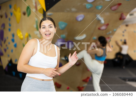 Portrait of slender smiling woman climber on background of climbing wall Portrait of slender smiling woman climber on background of climbing wall 106080440