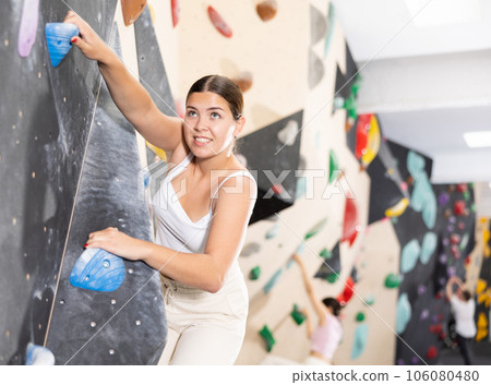 Young woman practicing rock climbing on climbing wall Young woman practicing rock climbing on climbing wall 106080480