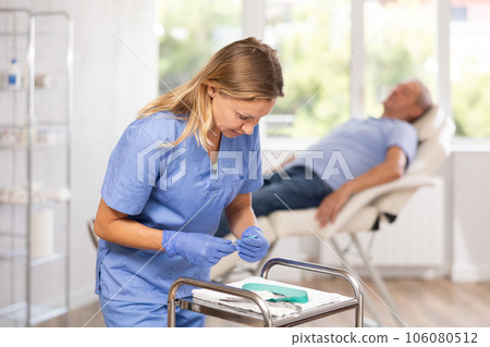 Adult woman doctor posing with syringe in medical office Adult woman doctor posing with syringe in medical office 106080512