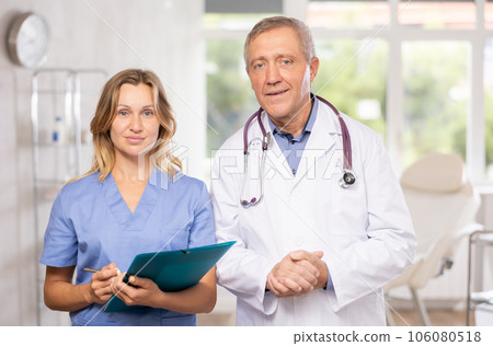 Elderly man and adult woman doctors posing in medical office 106080518
