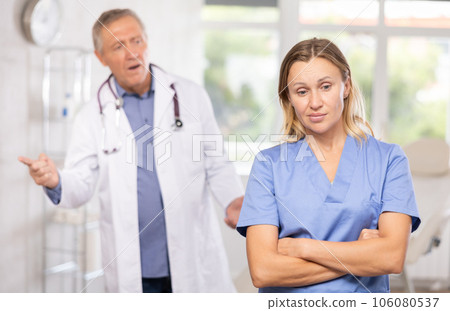 Elderly blurry male doctor swears at nurse for not fulfilling orders 106080537