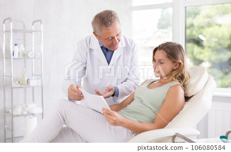 Man doctor give female patient medical documents for review before carrying out cosmetic procedure Man doctor give female patient medical documents for review before carrying out cosmetic procedure 106080584