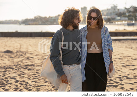 Handsome couple in love hugging while walking along the beach on sunny day Handsome couple in love hugging while walking along the beach on sunny day 106082542