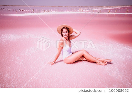 Woman in pink salt lake. She is in a bathing suit and a hat. Wanderlust photo for memory 106088662