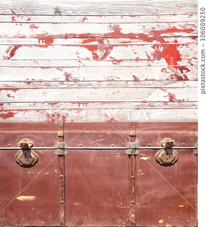 Retro background with red vintage chest upholstered in leather with brass snaps and wall with wooden boards. Product display template. Shabby chic style backdrop. Copy space for text 106089250