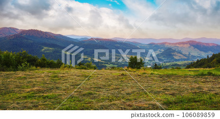sunrise over uzhanian pass. carpathian rural landscape in summer. hay drying on the meadow. village down in the valley sunrise over uzhanian pass. carpathian rural landscape in summer. hay drying on the meadow. village down in the valley 106089859