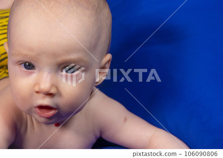 a baby on a blue background with a wooden rattle 106090806