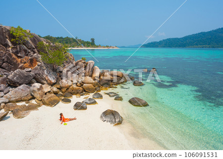 Asian solo traveler enjoys views of turquoise sea waters at Koh Kla beach during vacation on Ko Lipe, Thailand. Asian solo traveler enjoys views of turquoise sea waters at Koh Kla beach during vacation on Ko Lipe, Thailand. 106091531