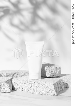 Empty white cream tube mockup on pumice stones for cosmetics product presentation. Minimal composition. Vertical studio photography. 106092657