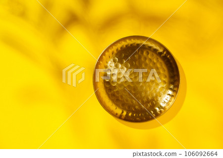 Flat lay blank product presentation scene made with bronze plate on yellow background with shade of leaves. Studio photography. 106092664