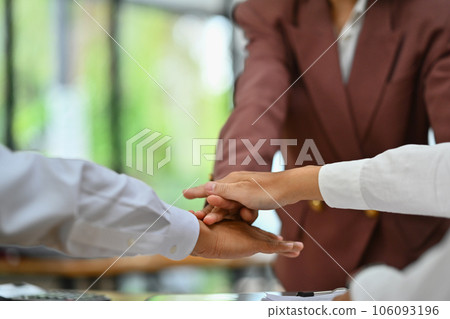 Businesspeople stacking hands over each other at meeting showing team unity, solidarity and teamwork Businesspeople stacking hands over each other at meeting showing team unity, solidarity and teamwork 106093196