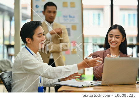 Asian male and female employee discussing project planning and advising on financial data report at office 106093225