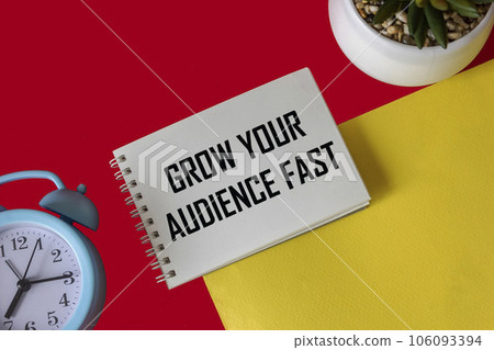 a clock and a cactus, in a white notebook there is an inscription - EXPAND YOUR AUDIENCE FAST 106093394